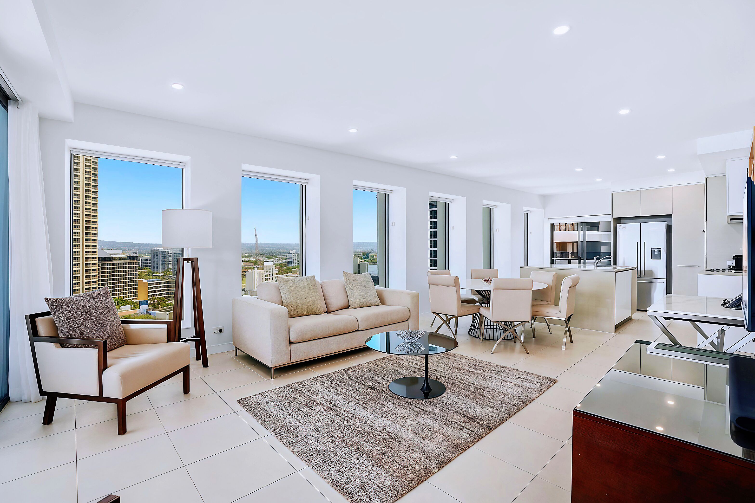 A modern living room with a sofa, armchairs, a coffee table, and a dining area.