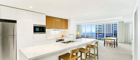 Una cocina moderna con una isla central, electrodomésticos de acero inoxidable y taburetes de madera.