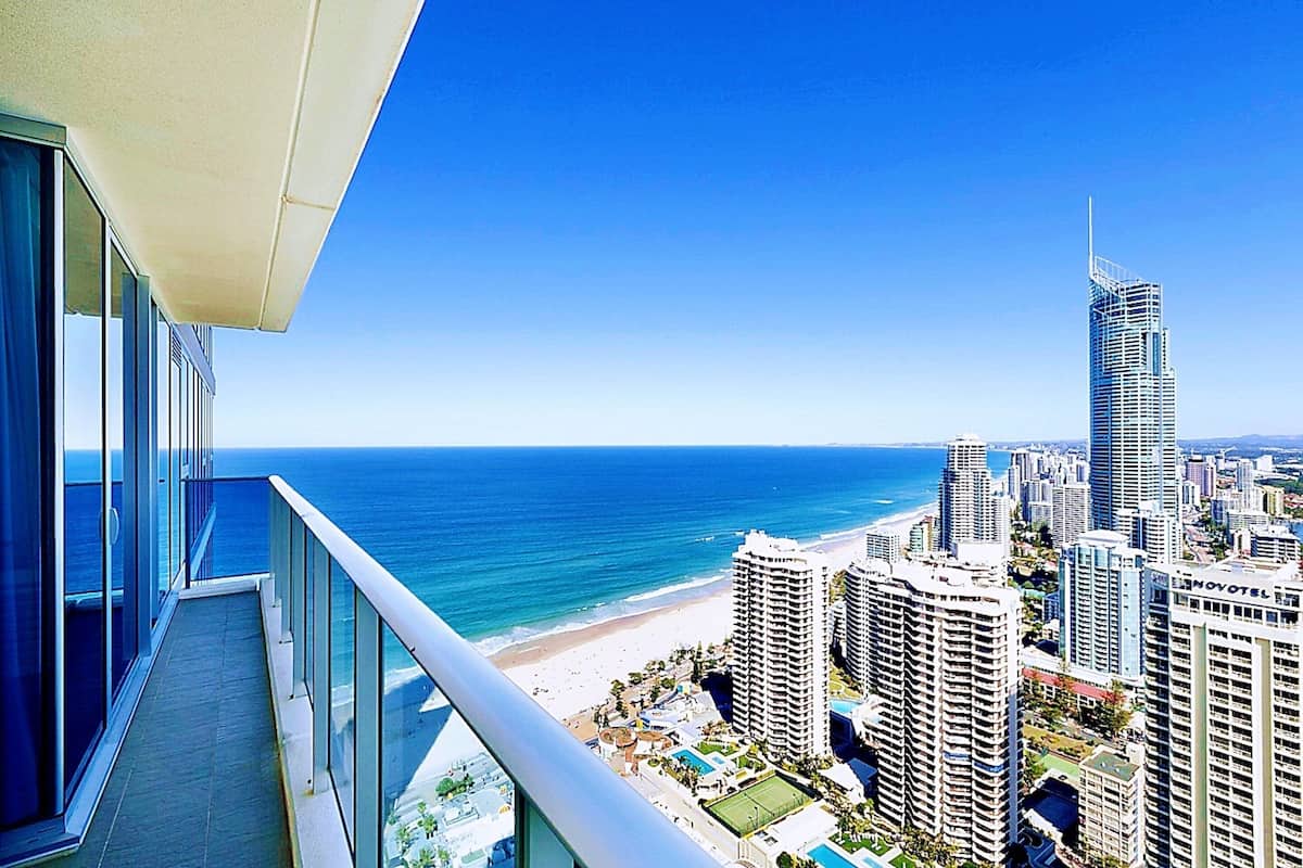 Een hoog hotel met een balkon met uitzicht op een strand en de oceaan.