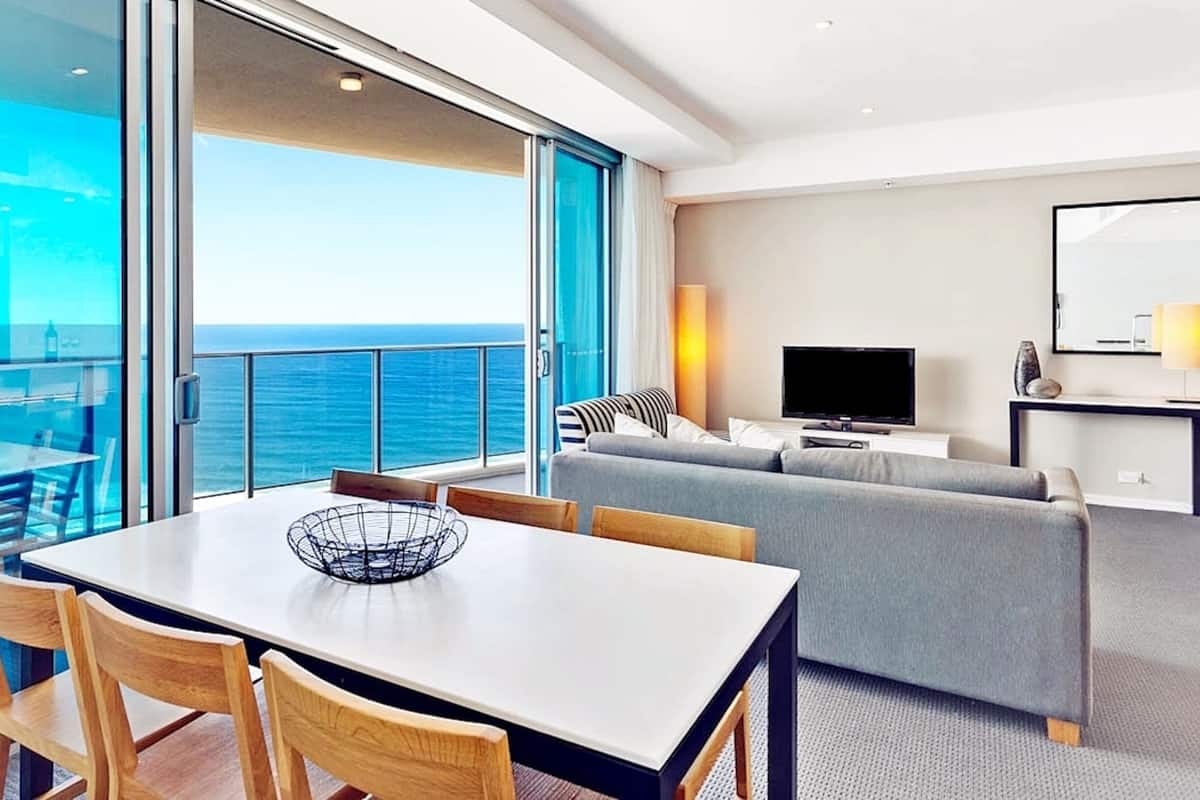 Een moderne hotelkamer met balkon, een eethoek, een zithoek en een televisie.