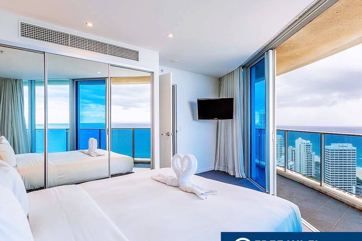 Een hotelkamer met een groot bed, een televisie en een balkon met uitzicht over de stad.