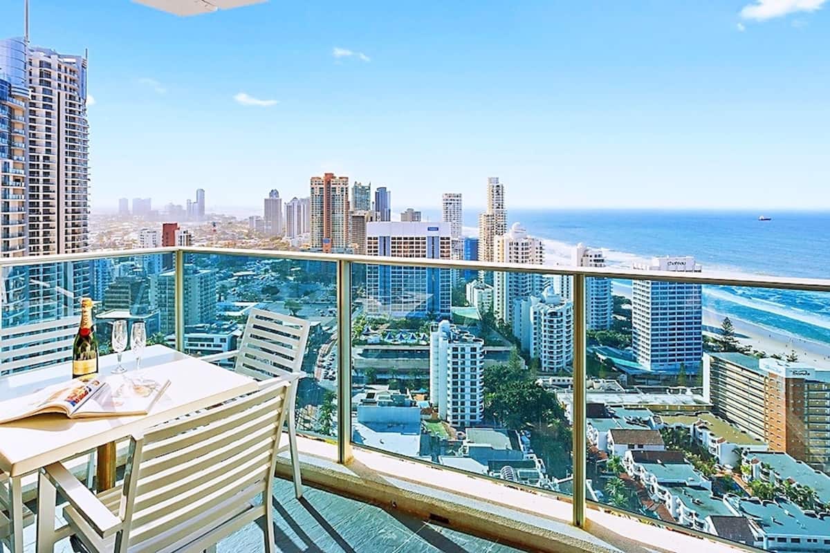 Een balkon met glazen balustrade, met uitzicht op een stadsbeeld en strand.