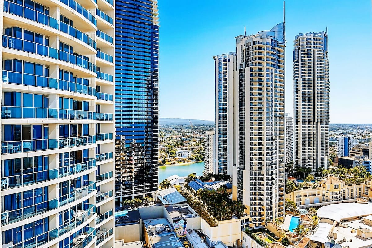 Een hoog hotel met meerdere balkons, een zwembad en uitzicht op de omliggende skyline.