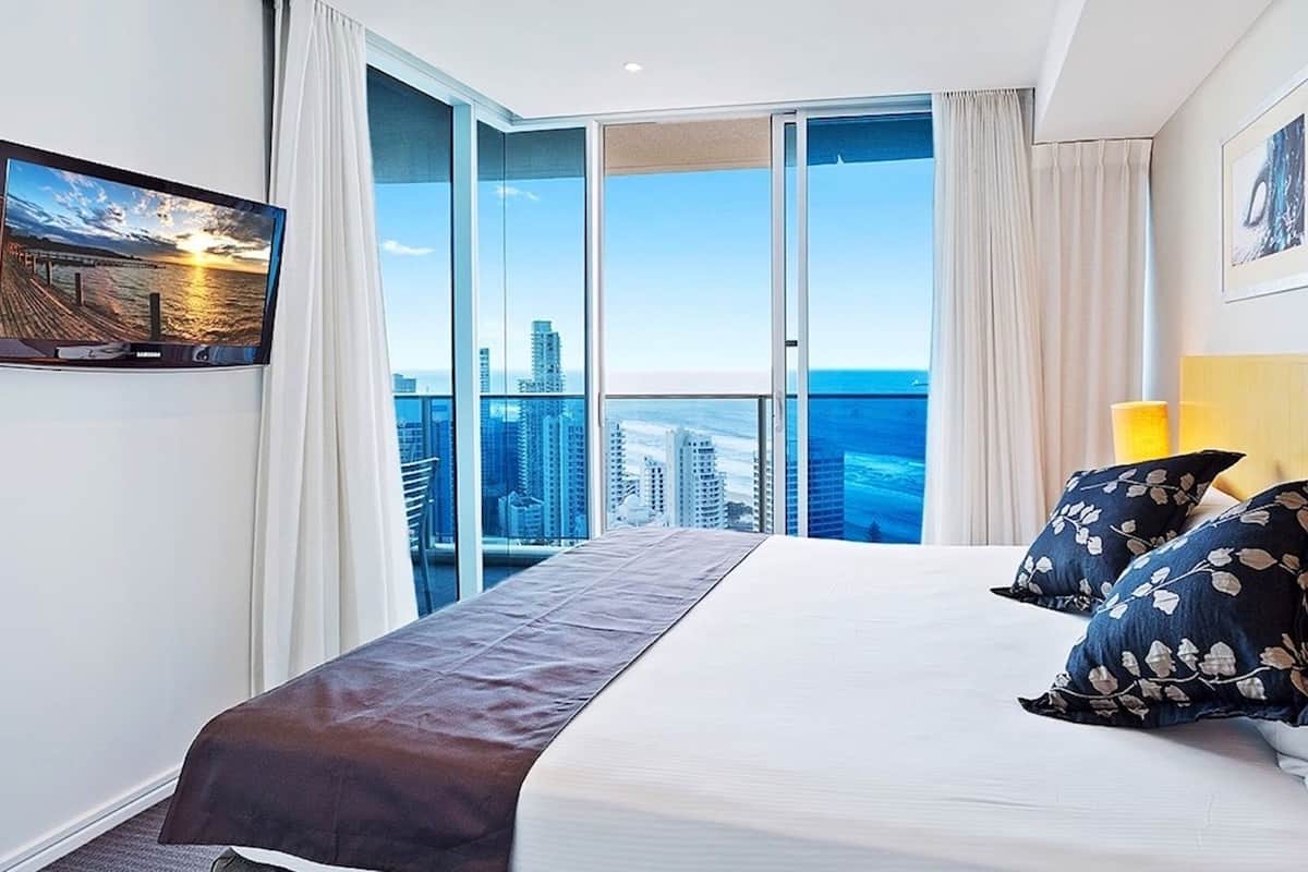 Een hotelkamer met een groot bed, stadszicht en een balkon.