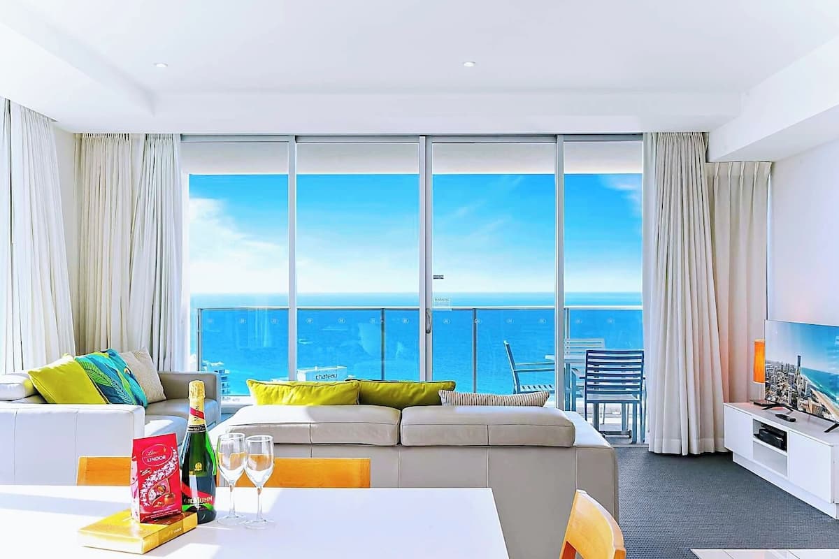 Een moderne hotelkamer met een ruim balkon, een zithoek, een eettafel en een televisie.