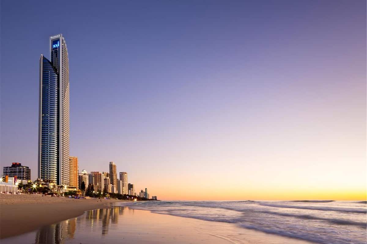 Stadsbeeld aan het strand met hoge gebouwen, waaronder een opvallend hotel met een 'SOU'-bord.