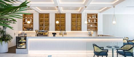 Un espace bar moderne doté d’un comptoir en marbre, de meubles en bois et de luminaires suspendus.