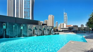 A swimming pool with clear blue water, surrounded by modern buildings and a city skyline in the background. - Circle On Cavill Surfers Paradise Apartments-Holiday Paradise (Surfers Paradise)