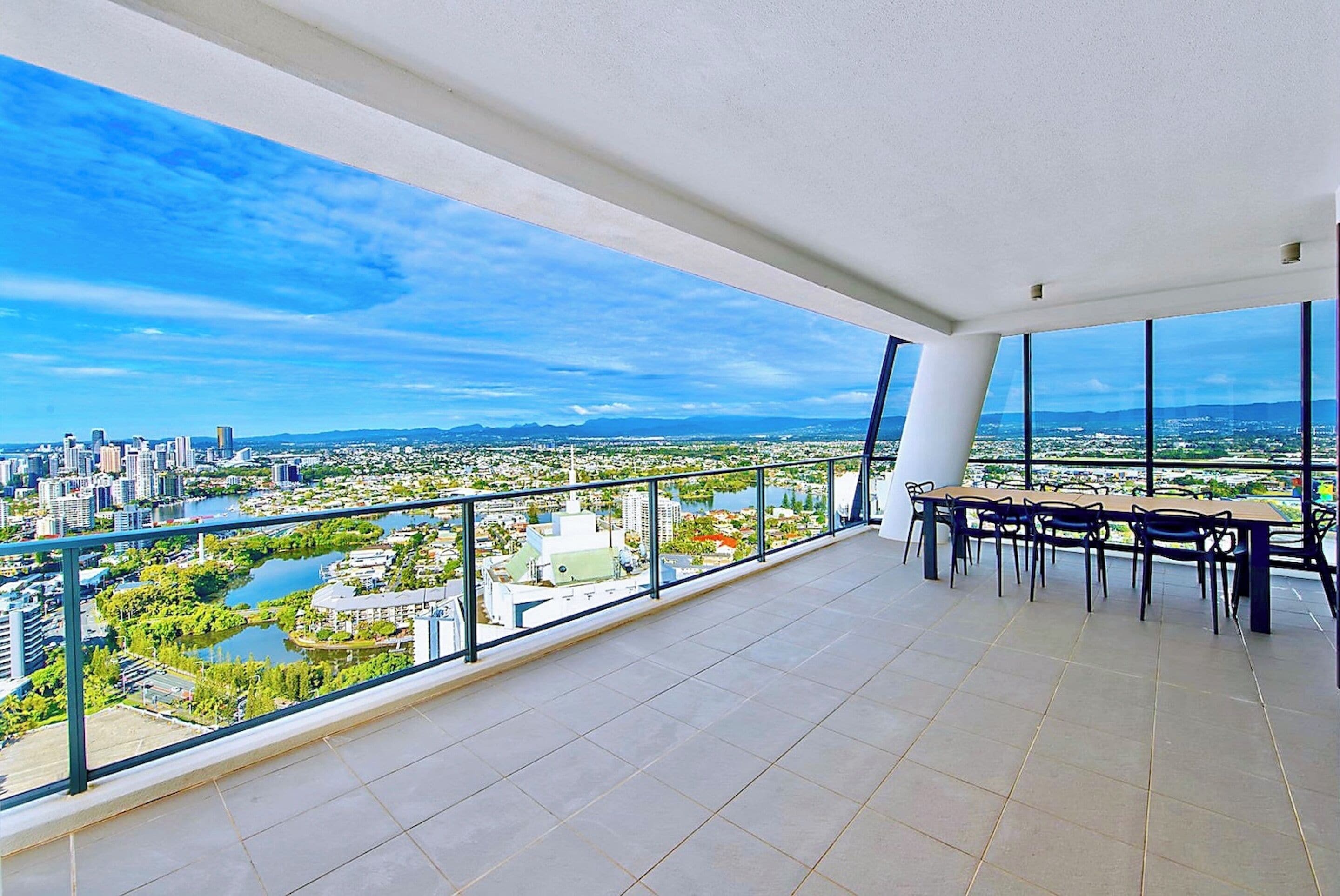 A spacious balcony with a clear view of a cityscape, including buildings and a river.