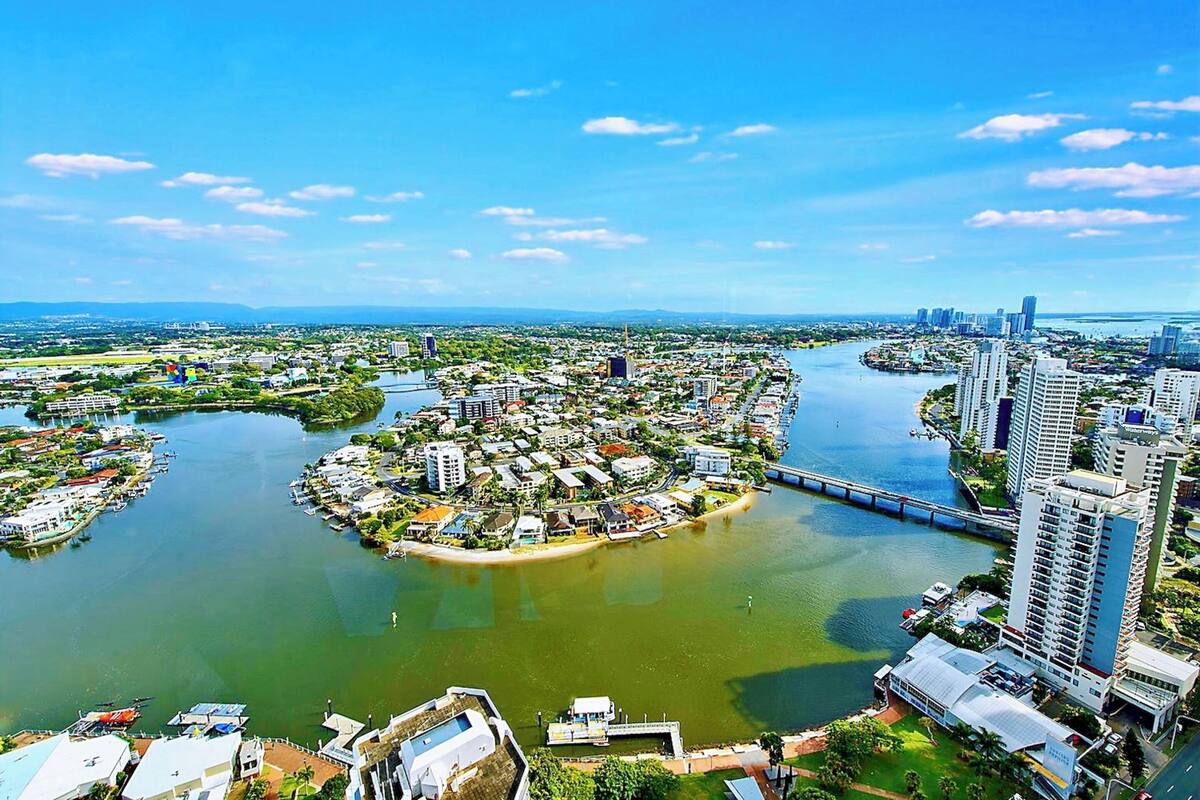 An aerial view of a coastal city with a river, bridges, and high-rise buildings.