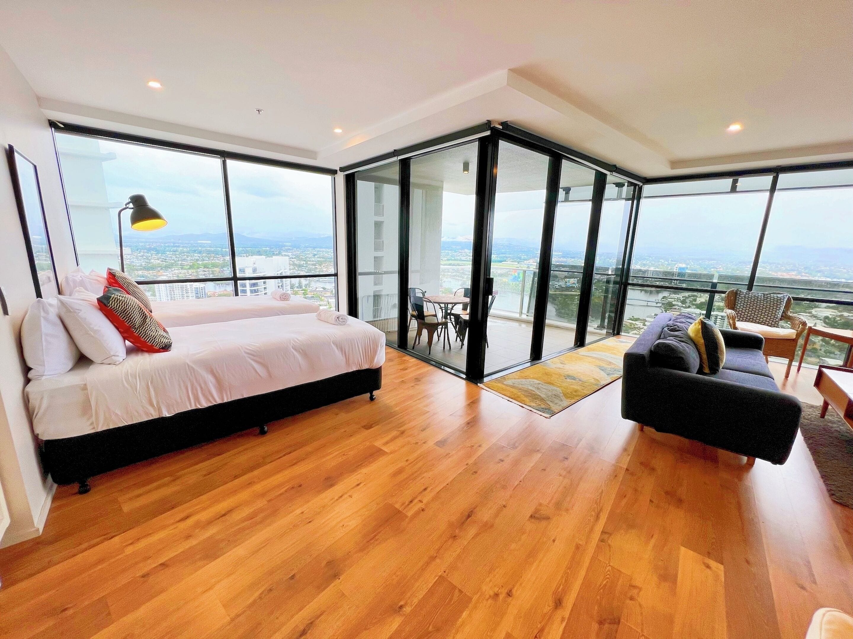Une chambre moderne avec un grand lit, un canapé et un balcon offrant une vue sur la ville.