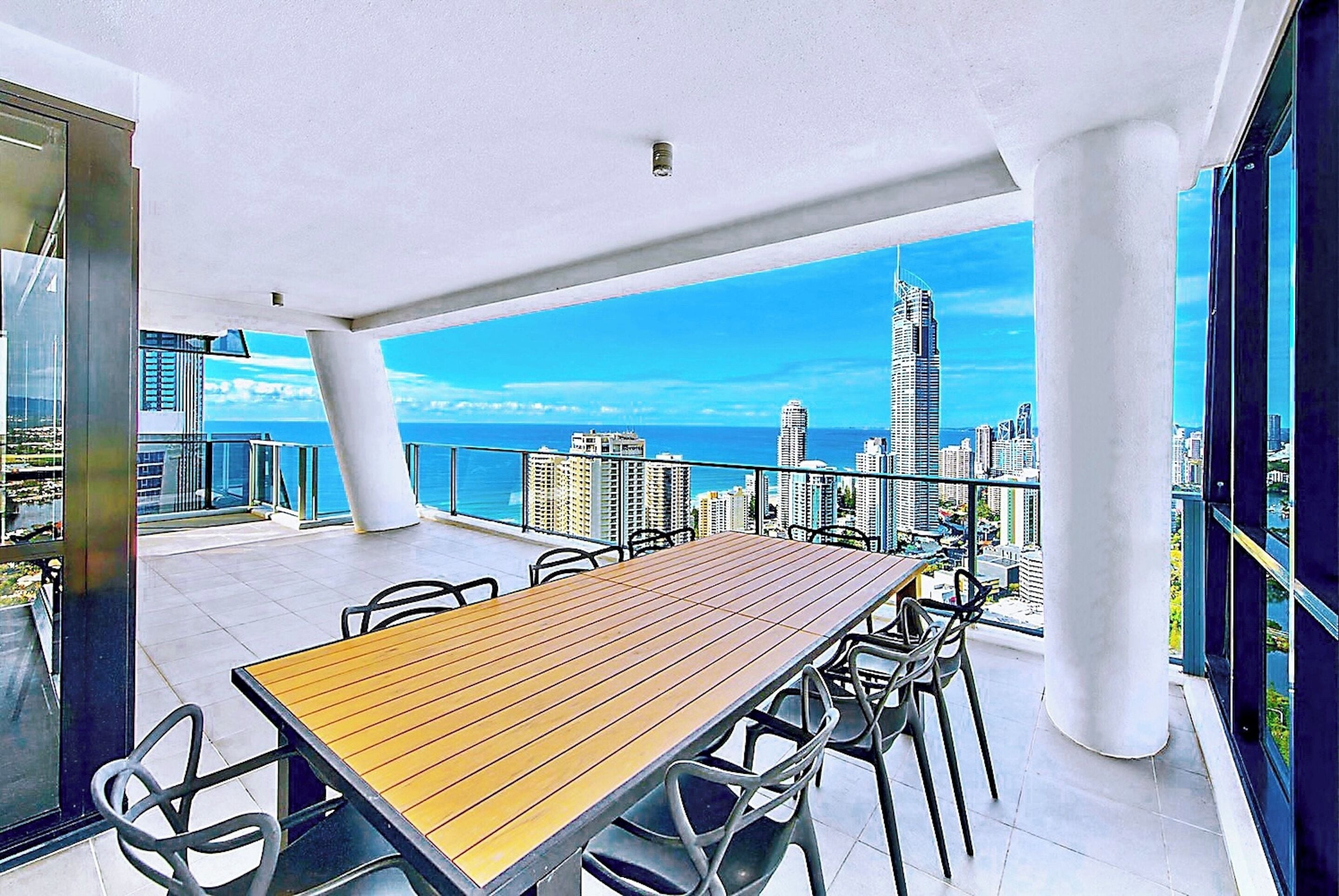 A rooftop terrace with a wooden table and chairs, offering a city skyline view.