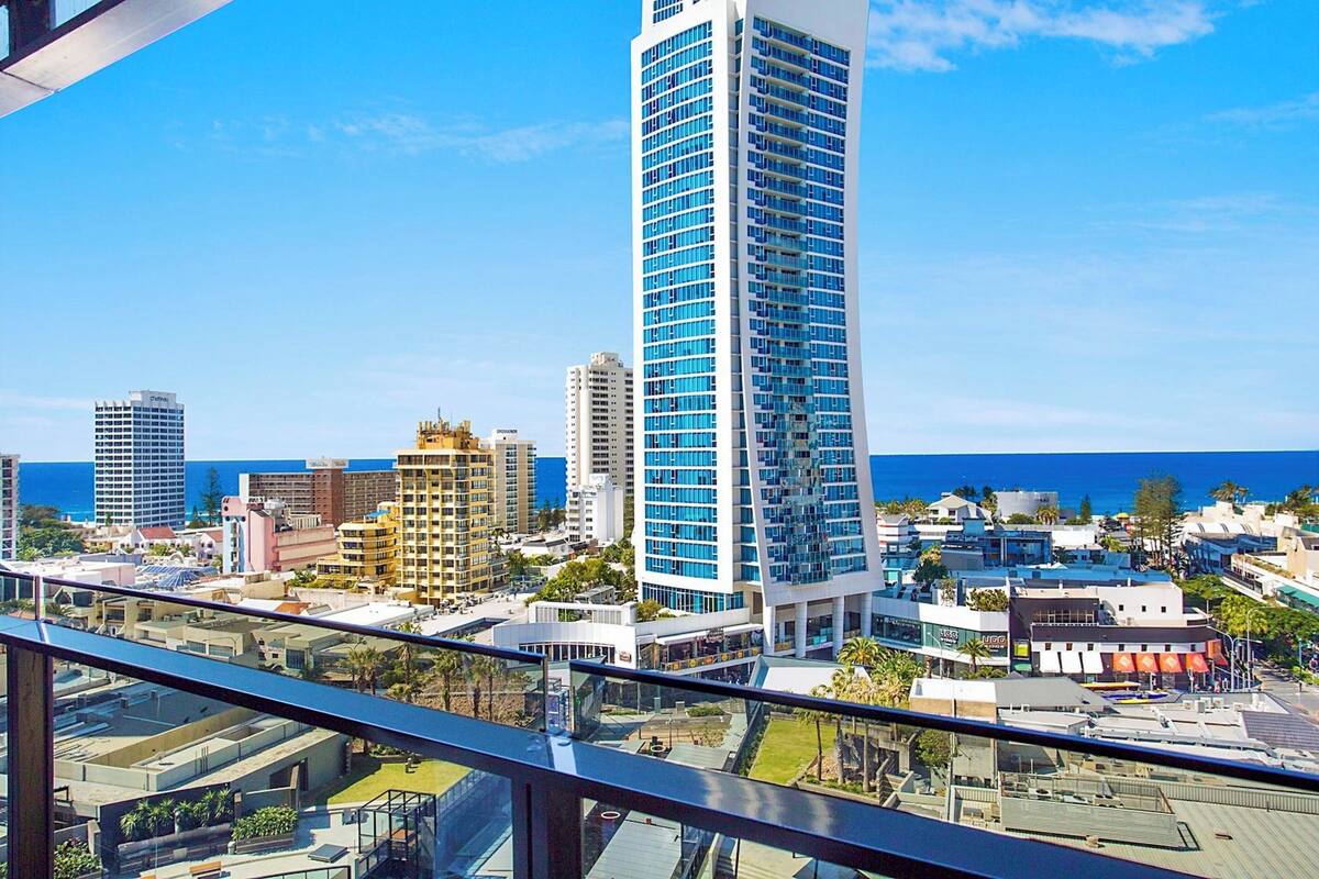 A high-rise building with a modern design, surrounded by other buildings and a clear blue sky.