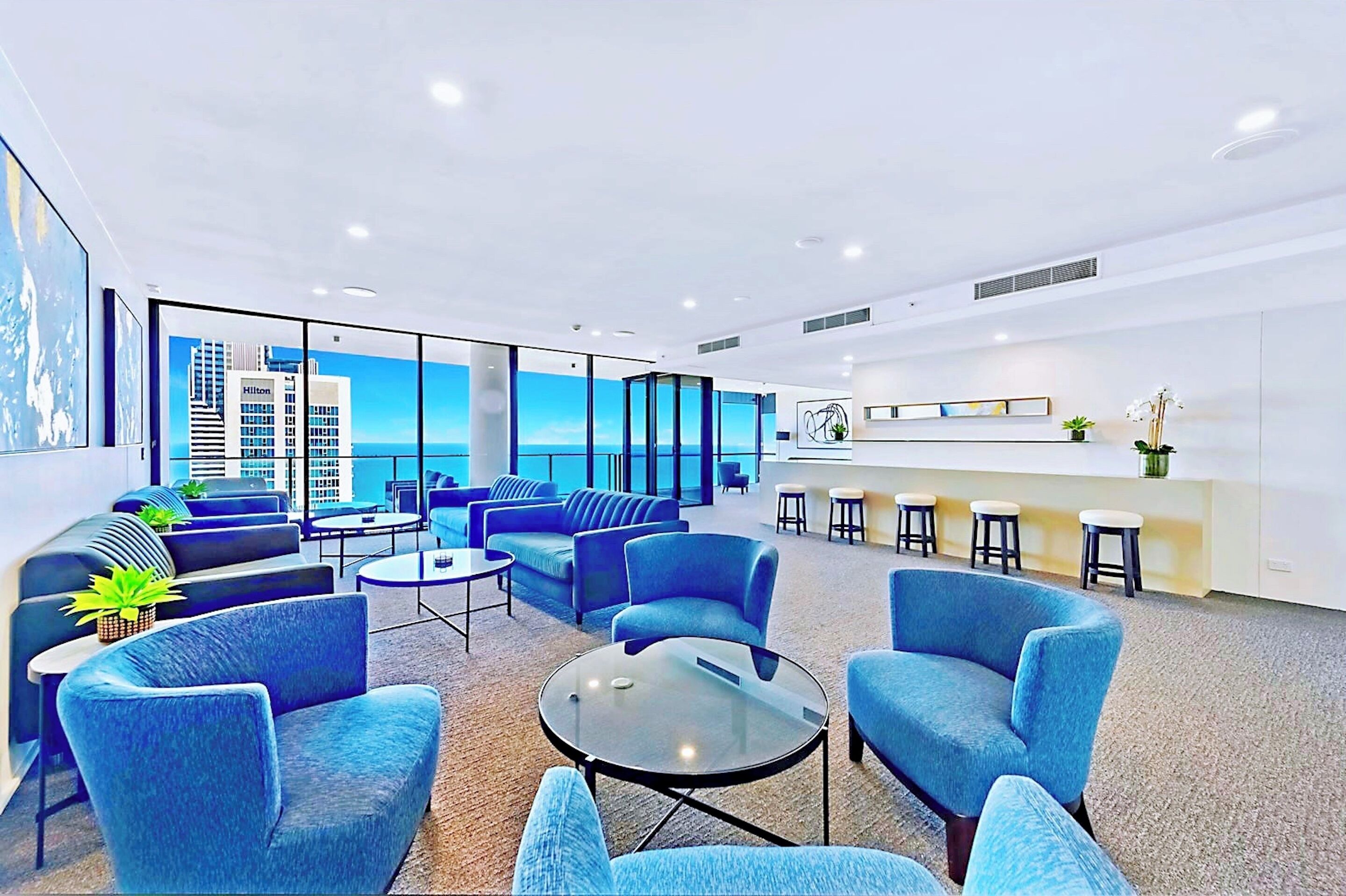 A modern hotel lobby with blue seating, a reception desk, and large windows offering a city view.