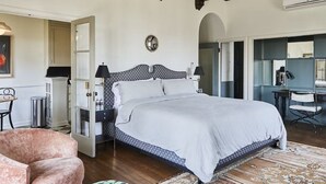 Une chambre à coucher comprenant un lit, des tables de chevet, une chaise, un bureau et un miroir.