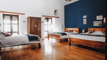 Une chambre avec deux lits en bois, une armoire et un mur d’accent bleu.