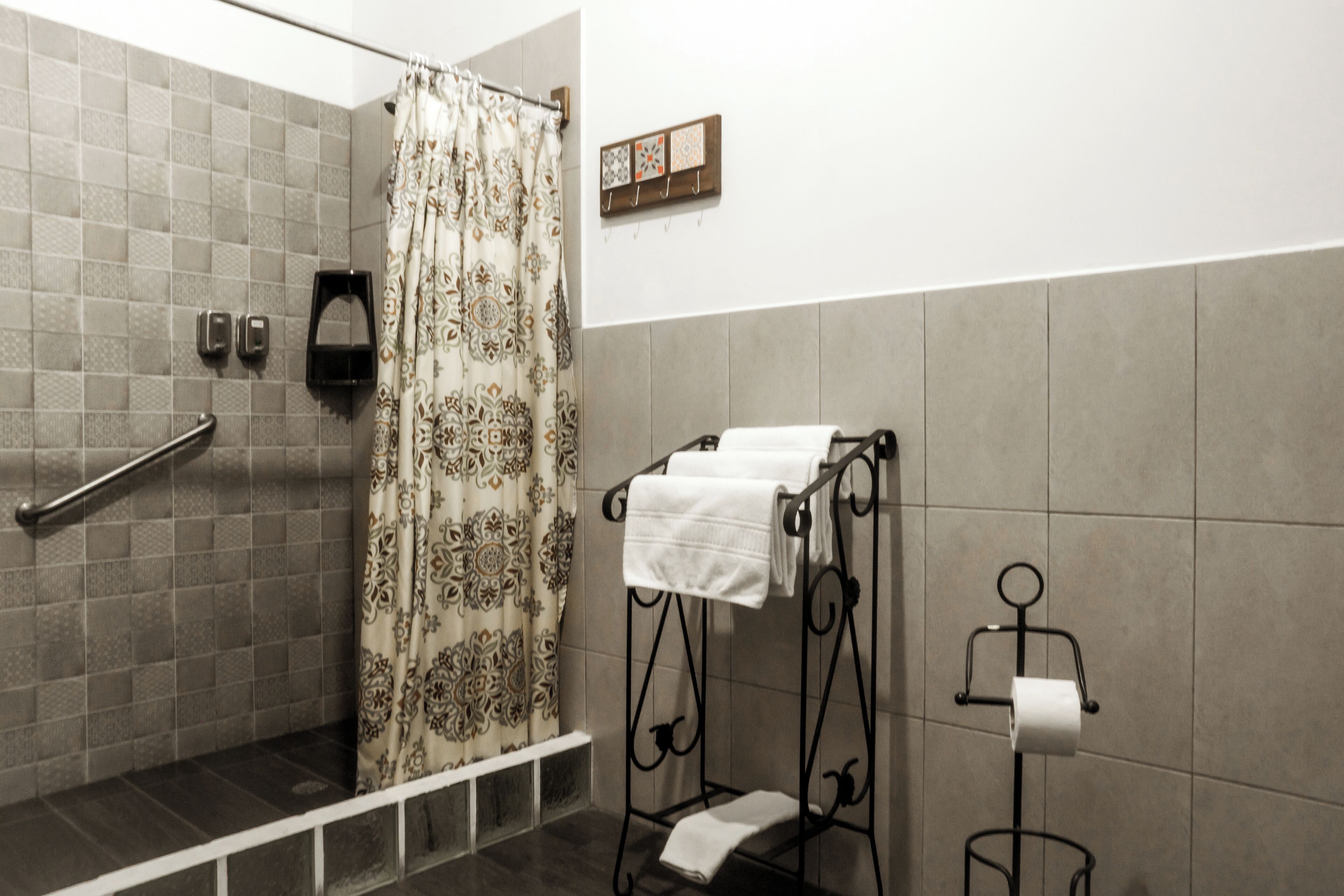 A bathroom with a shower, a towel rack, and a toilet paper holder.