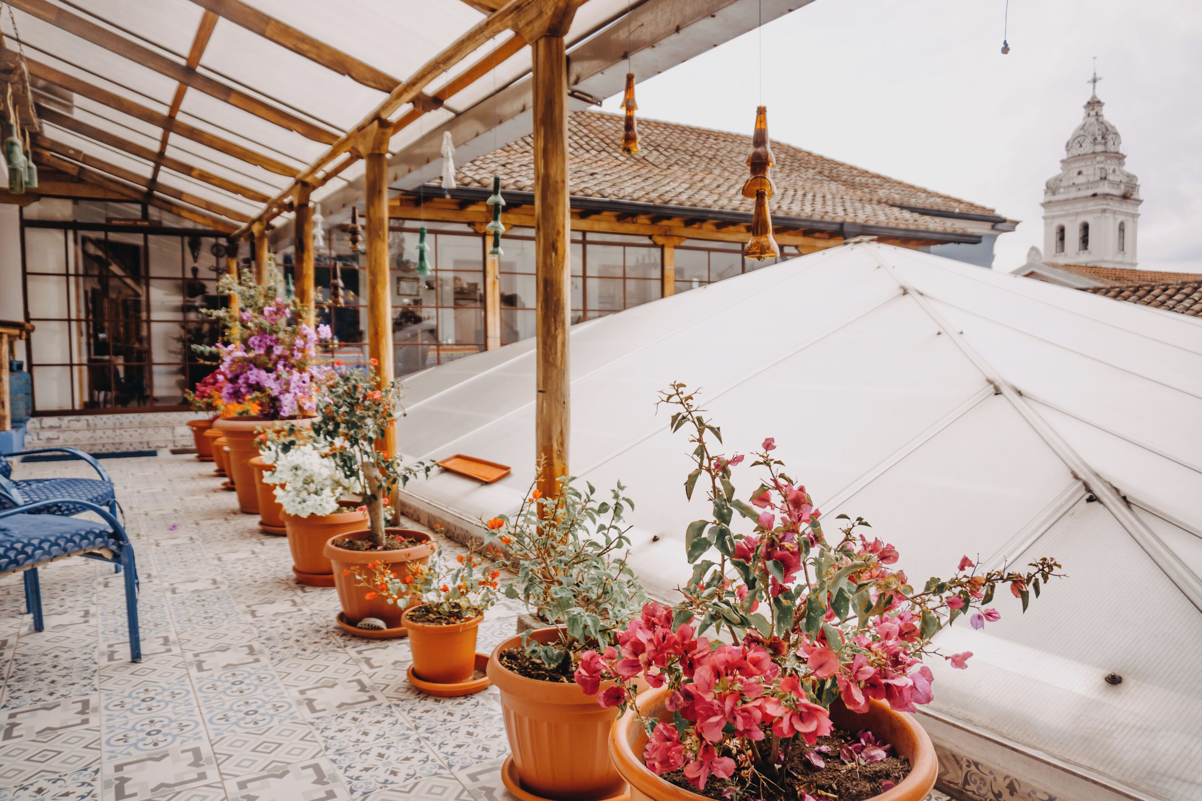 A covered outdoor area with potted plants and a blue chair.