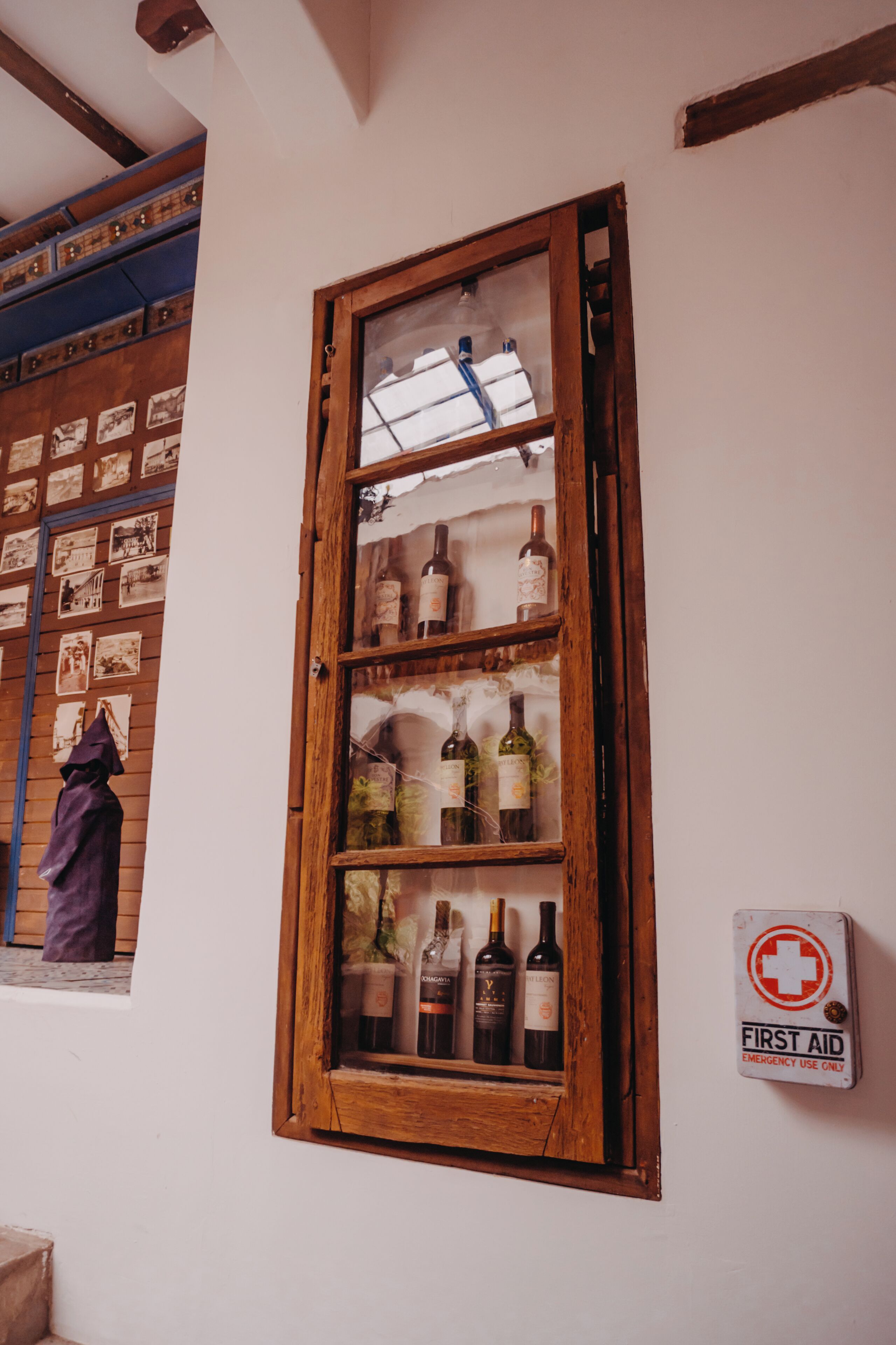 A wooden wine cabinet with glass doors containing various bottles.
