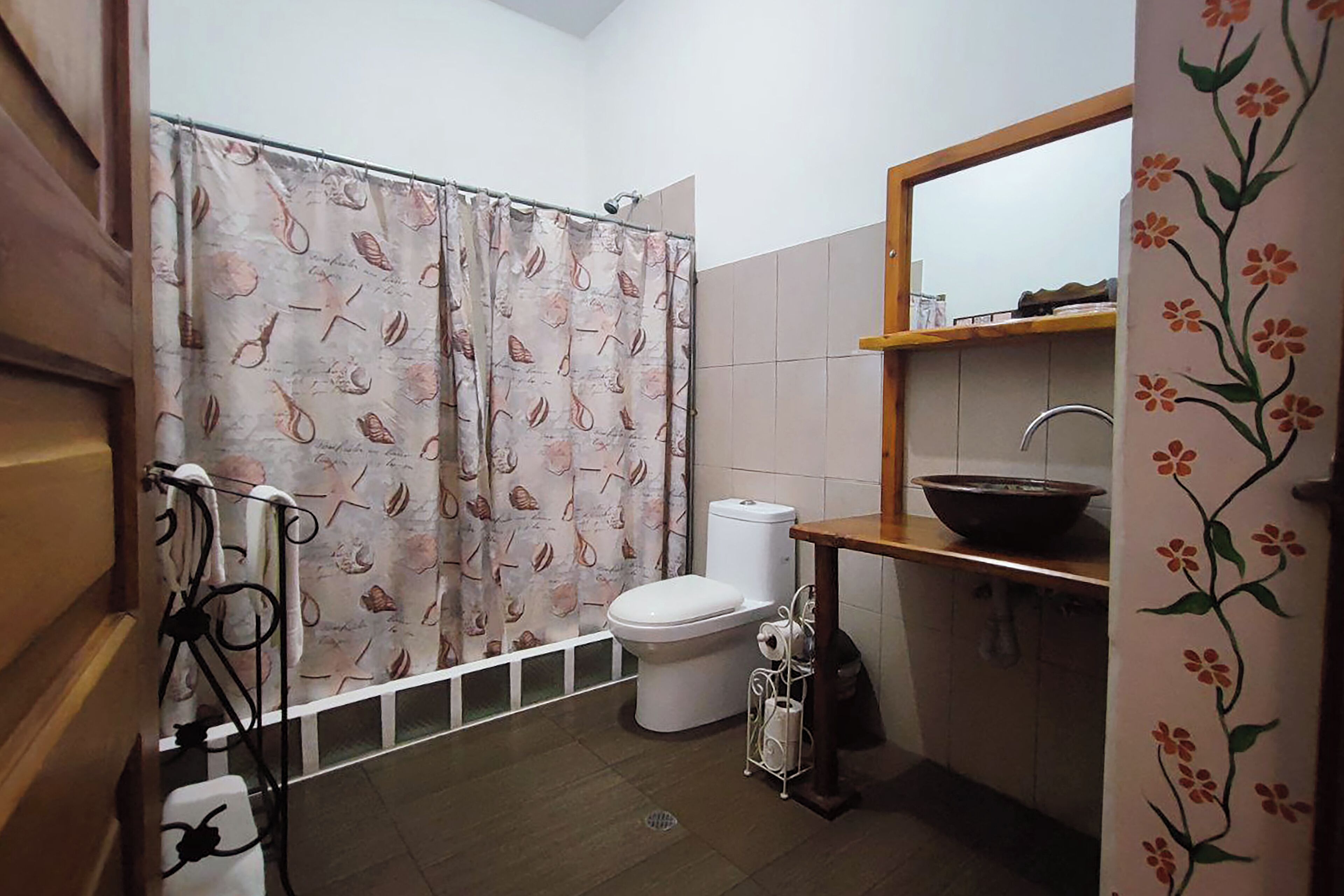 Un baño con cortina de ducha, inodoro, lavabo y un espejo sobre el lavabo.