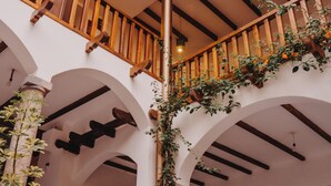 A multi-level atrium with wooden railings, arches, and potted plants. - Hotel Casa Alquimia (Quito)