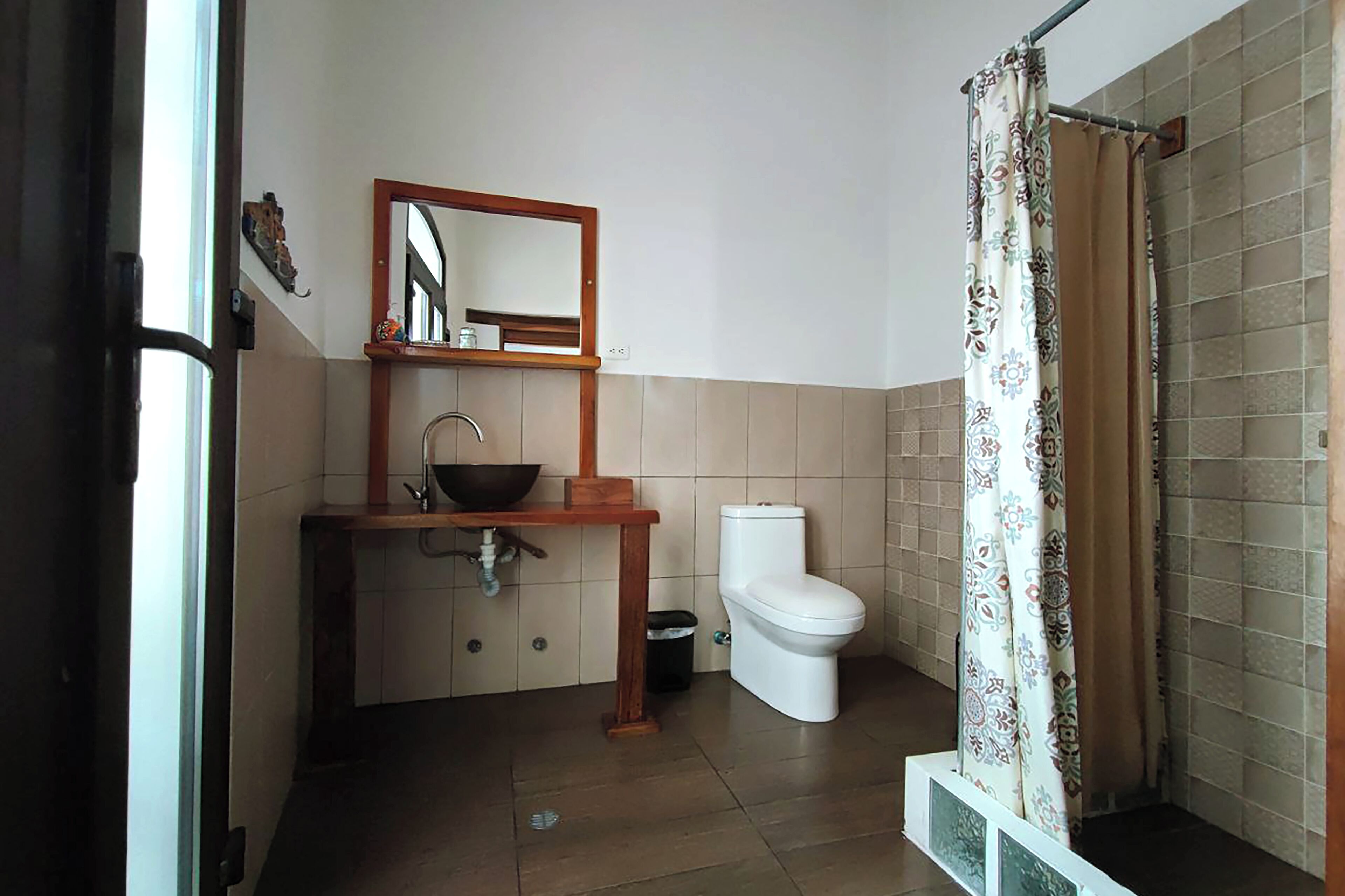 A bathroom with a toilet, sink, and mirror.