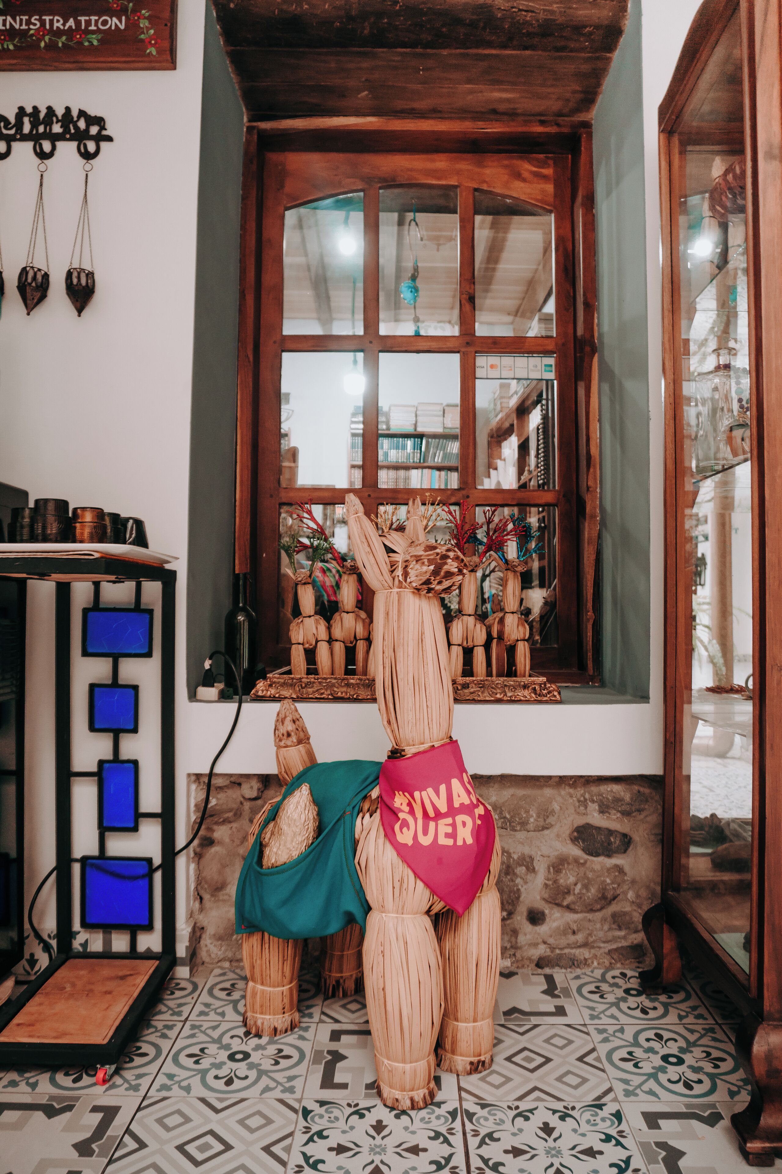 A rustic interior with a wooden bear statue, a window with decorative items, and a tiled floor.