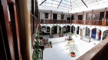 A spacious atrium with a high ceiling, multiple levels, and a central courtyard with potted plants.