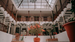 A spacious atrium with a high ceiling, multiple levels, and a central potted plant. - Hotel Casa Alquimia (Quito)