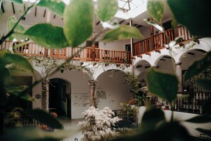An indoor courtyard with arches, a wooden staircase, and potted plants. - Hotel Casa Alquimia (Quito)
