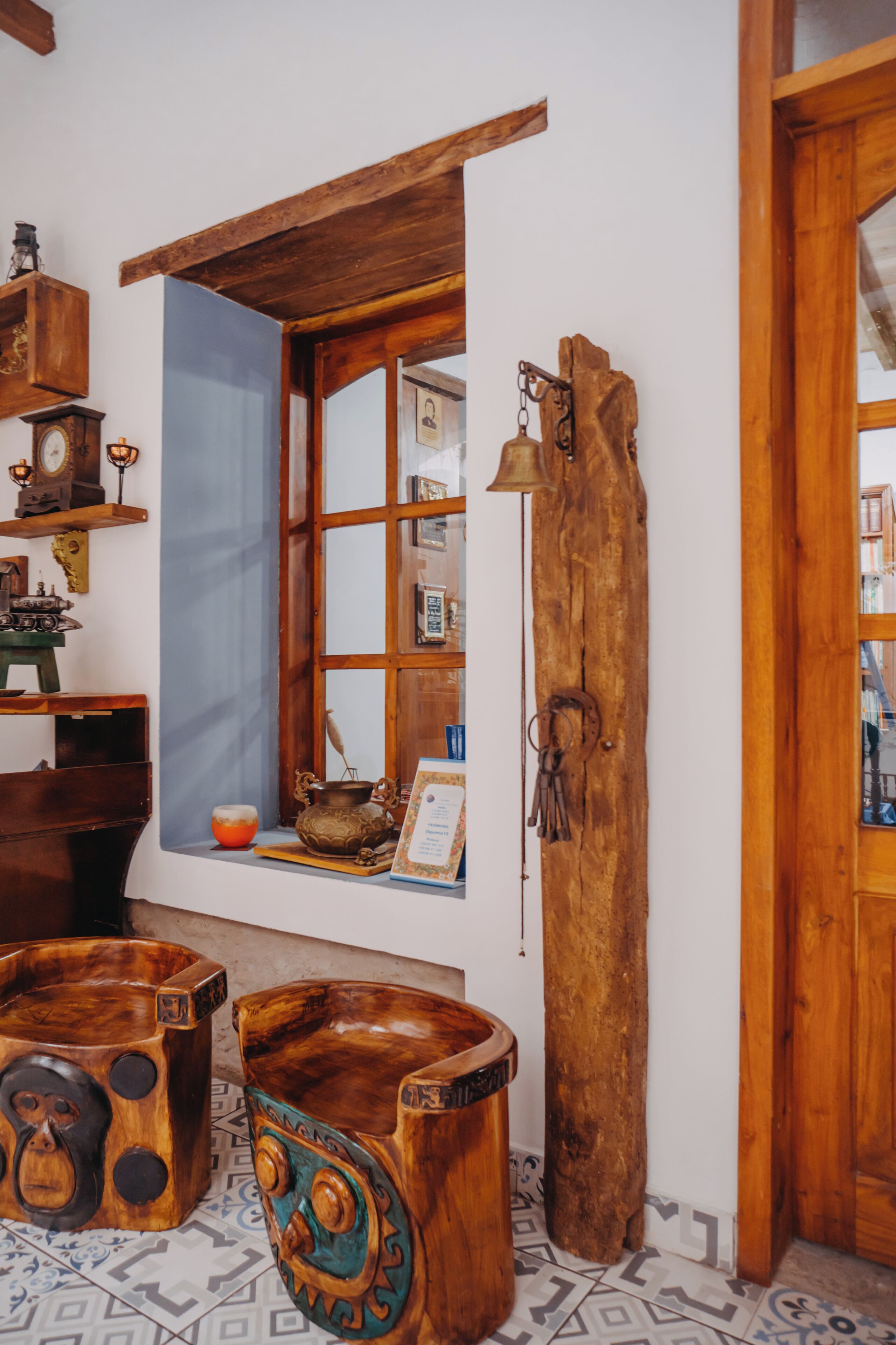 A rustic room with a wooden bench, a window with a blue curtain, and a wooden door.
