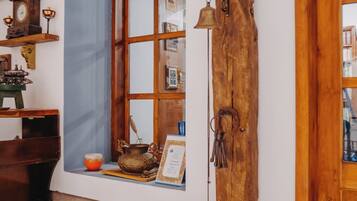 Una habitación rústica con un banco de madera, una ventana con cortina azul y una puerta de madera.