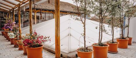 A covered outdoor area with a white cushioned seating area and potted plants.