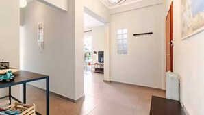 A spacious hallway with a dining area on the left, a radiator on the right, and a door leading to another room. - AthenSunapartment  Top floor / 5" metro (Athina)