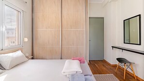 A bedroom with a bed, a wooden wardrobe, a desk with a chair, and a mirror on the wall. - AthenSunapartment  Top floor / 5" metro (Athina)