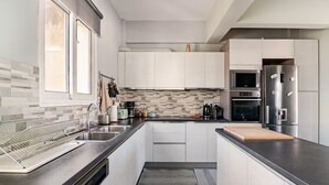 A modern kitchen with white cabinets, stainless steel appliances, and a tiled backsplash. - AthenSunapartment  Top floor / 5" metro (Athina)