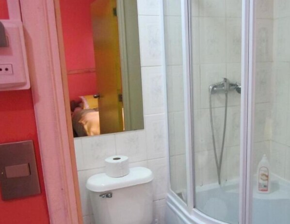 Un baño con inodoro, ducha y espejo.