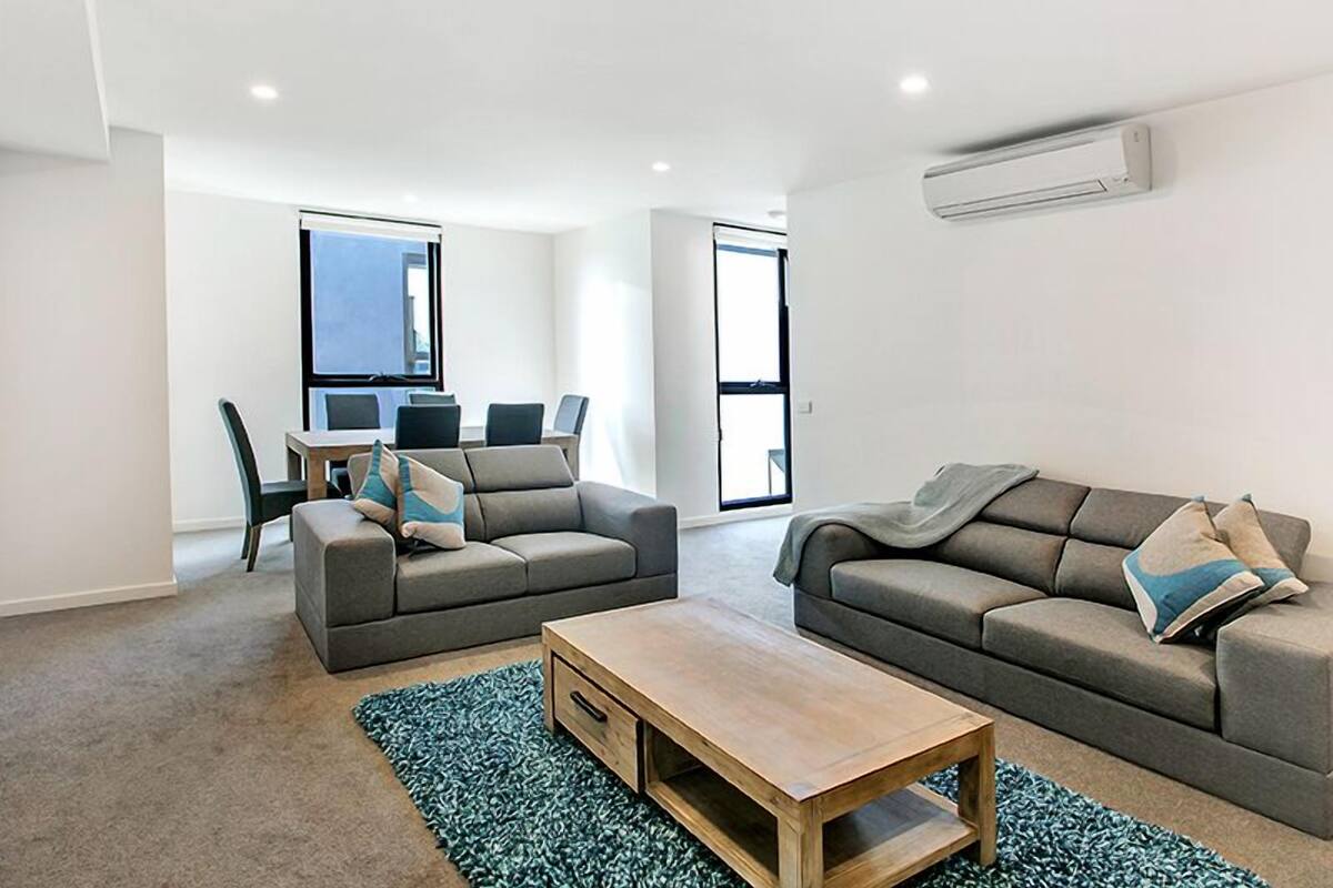 A modern living room with two sofas, a coffee table, and a dining area with chairs and a table.