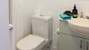 Ein kleines, sauberes Badezimmer mit Toilette, Waschbecken und Spiegel.