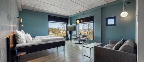 A modern room with a bed, a sofa, a small table, and a TV.