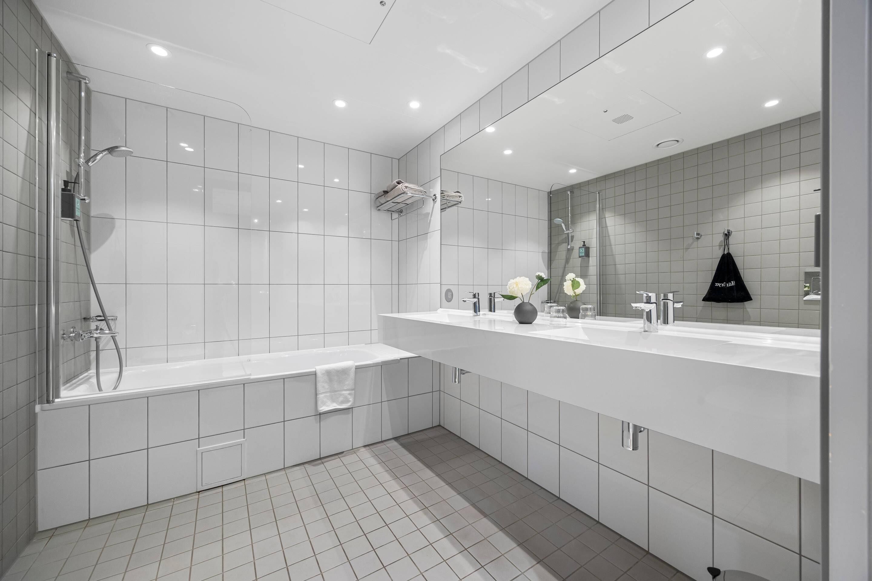 Een moderne badkamer met een bad, een douche, een wastafel met spiegel, en een toilet.