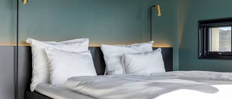 Una cama con ropa blanca, dos lámparas de noche y una ventana con vistas.