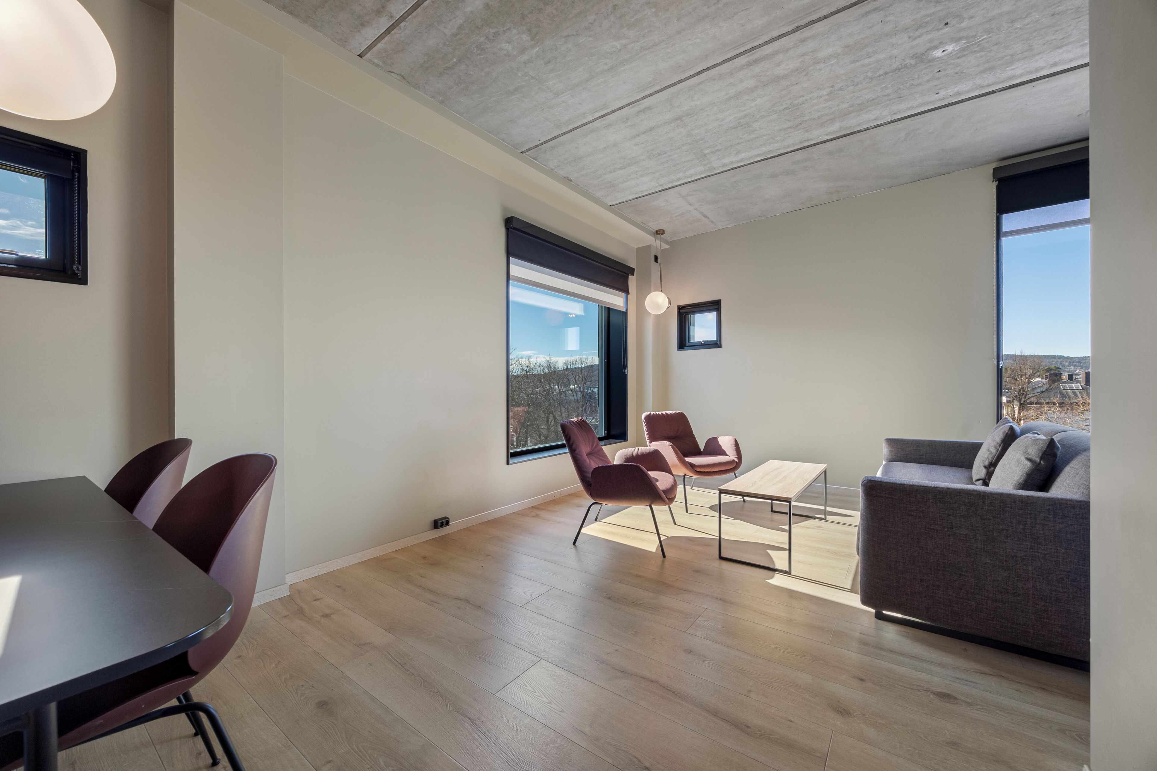 A modern living room with a dining area, large windows, and a view of the outdoors.