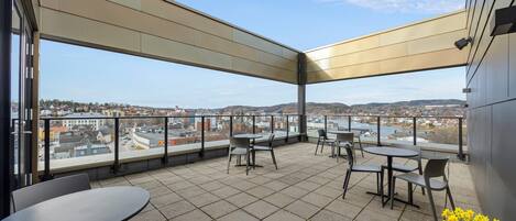 Una terraza con mesas y sillas, vistas de la ciudad y un arreglo floral.