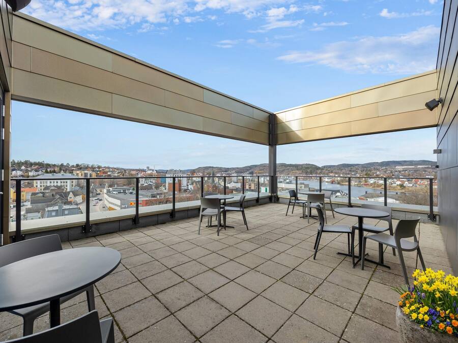 Une terrasse avec des tables et des chaises, une vue sur la ville et un arrangement floral.