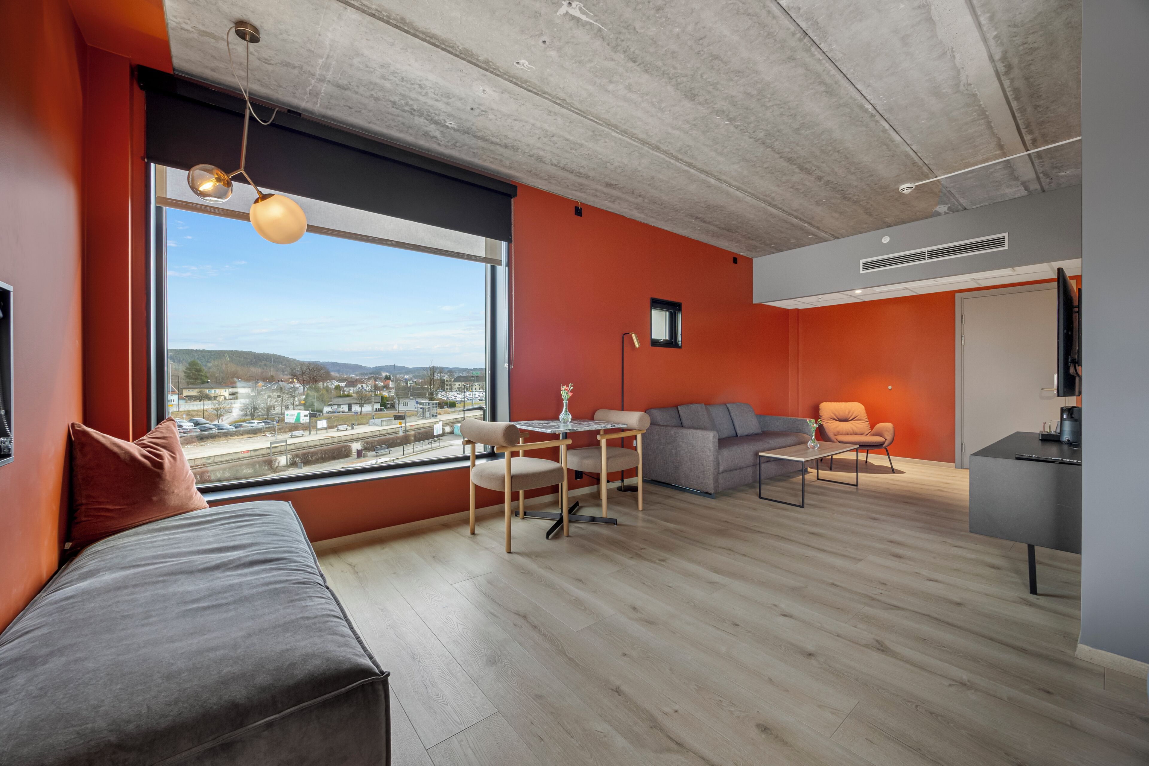 Una sala de estar moderna con un ventanal grande, un sofá, una mesa de centro y una zona de cocina.