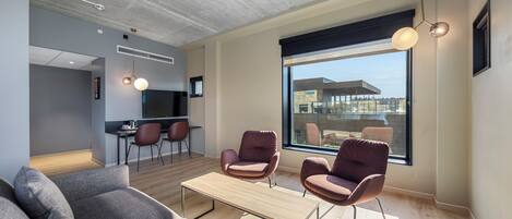A modern living room with a sofa, two armchairs, a coffee table, and a large window with a view.