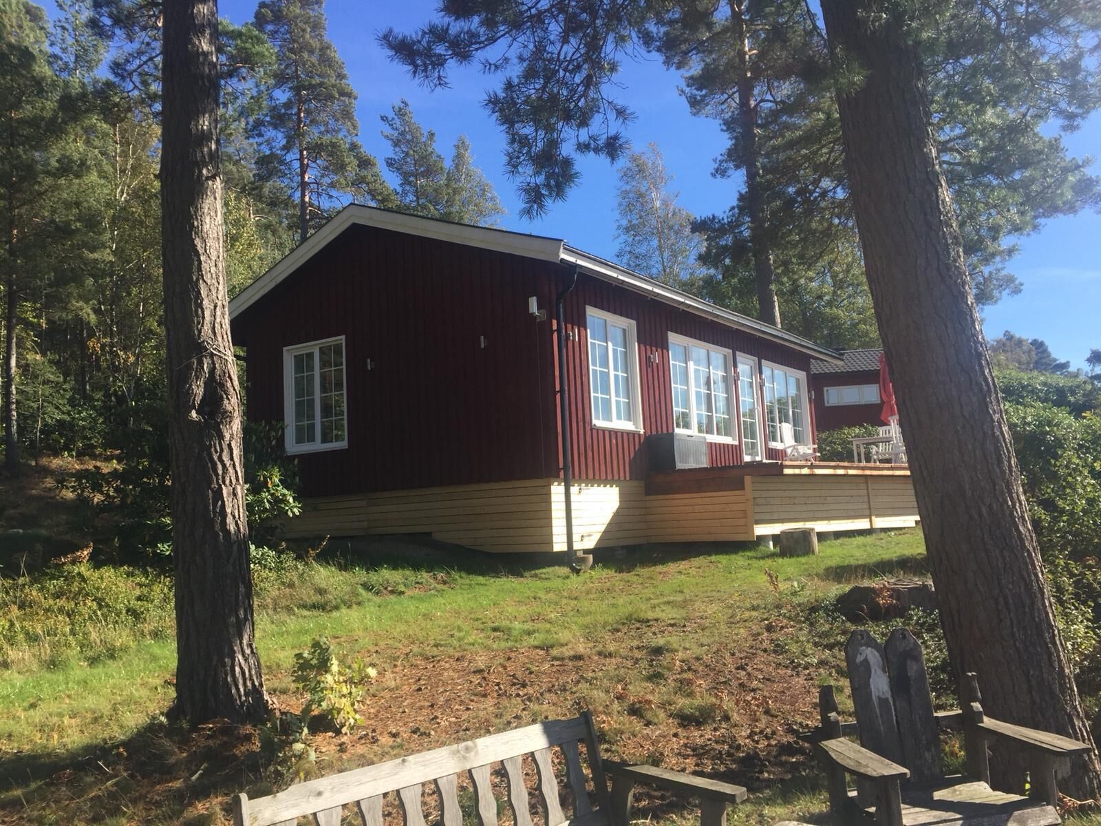 En stuga med en stor veranda, omgiven av träd.