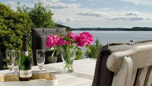 A wooden table with a bottle of wine, glasses, and a vase of flowers.