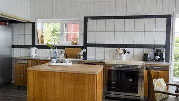 Une cuisine moderne dotée d’un îlot central en bois, d’appareils électroménagers en acier inoxydable et d’une fenêtre donnant sur un paysage verdoyant.